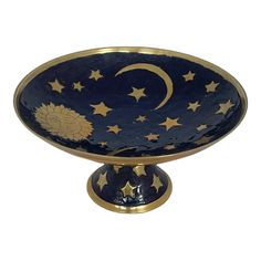 a blue bowl with gold stars and the moon on it's side, sitting in front of a white background