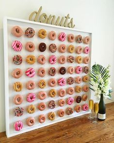 there is a large display of doughnuts on the wall next to a vase with flowers