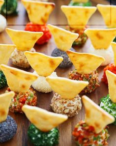 several different types of snacks are arranged on a wooden table with other food items in the background