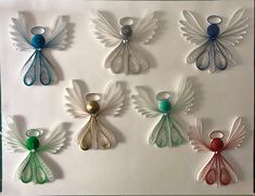 an assortment of glass angel ornaments on a white sheet with green and blue trimmings