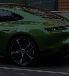 a green sports car parked on the side of the road in front of a brick building