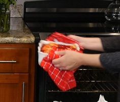 a person is cleaning an oven with a red towel and some food in the dishwasher