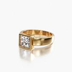 a gold ring with a princess cut diamond in the center, on a white background