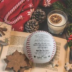 a baseball sitting on top of an open book next to a candle and christmas decorations