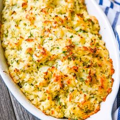 a casserole dish with cheese and herbs in it on a blue and white towel