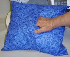 a person holding onto a blue pillow on a bed