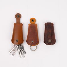 three leather key fobs are lined up next to each other