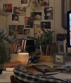 a computer monitor sitting on top of a desk next to a lamp and pictures hanging on the wall