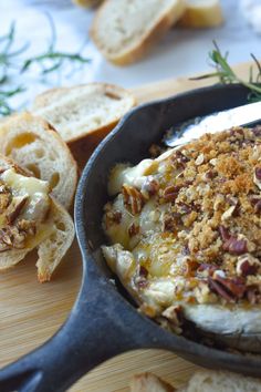 a skillet filled with food sitting on top of a cutting board next to slices of bread