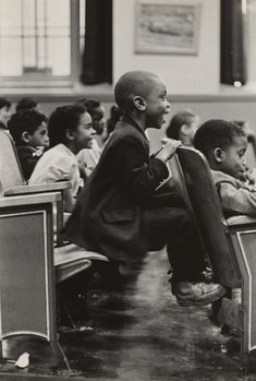 a black and white photo of children sitting at desks with their backs to the camera