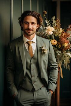 a man wearing a suit and tie standing next to a vase with flowers in it