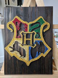 the hogwarts crest is made out of wood and beaded with colorful beads