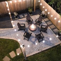 an outdoor fire pit surrounded by chairs and lights