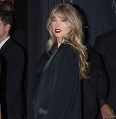 the woman is wearing a black suit and red lipstick