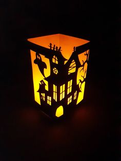 a paper lantern that is shaped like a house with cats and bats on the roof