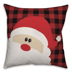 a red and black plaid pillow with a santa claus face on the front, while it is