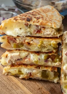 a stack of quesadillas sitting on top of a wooden table next to a bowl