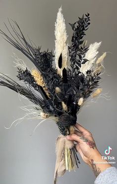 a person holding up a fake plant with black and white feathers on it's head