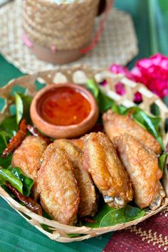 a basket filled with fried food next to a bowl of sauce on top of a table