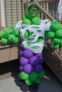 a man in a costume made out of green and purple balloons is standing on the steps