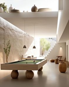 a pool table in the middle of a room with stairs leading up to an open floor plan