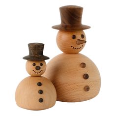 two wooden snowmen wearing hats and standing next to each other