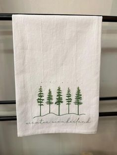 a white towel hanging from a black metal rack with trees on it and the words, not all those are left behind