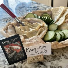 a bowl filled with cucumbers and chips next to a sign that reads moby - dip and chips