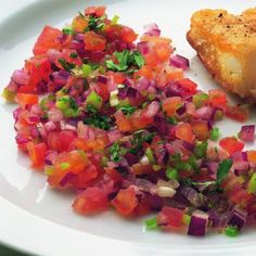 a white plate topped with meat and veggies next to a slice of bread