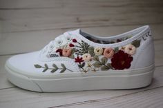 a pair of white shoes with floral embroidered on the soles and lace at the top