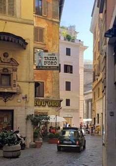 an old car is parked in the middle of a cobblestone street lined with buildings