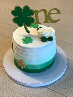 a cake with white frosting and green icing on a plate next to a one sign