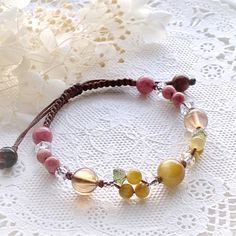 a close up of a bracelet on a doily with flowers in the back ground