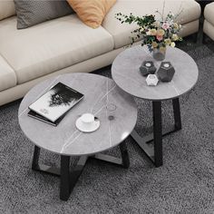 two round tables sitting on top of a carpeted floor next to a white couch