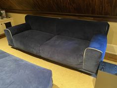 a blue couch sitting on top of a floor next to a wooden table and chair