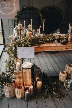 candles and greenery are arranged on the floor next to a table with a sign