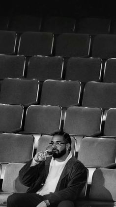 a man sitting on a bench in front of a row of chairs drinking from a cup