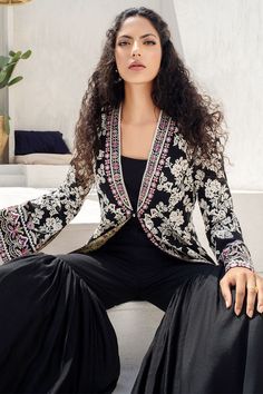 Delicate embroidery rendered in hues of cream and buttermilk decorates this black embroidered front open jacket on khaddi corduroy. The jacket edges are finished with a floral border and exude a classic yet modernized vibe. It is paired with matching two legged dhaka trousers. Luxury Designer Outerwear With Chikankari Embroidery, Luxury Long Nehru Jacket With Chikankari Embroidery, Luxury Traditional Outerwear With Embroidered Border, Luxury Embroidered Blazer For Semi-formal Occasions, Luxury Winter Nehru Jacket With Chikankari Embroidery, Luxury Floral Embroidery Outerwear For Eid, Luxury Women's Nehru Jacket For Eid, Luxury Brocade Nehru Jacket With Chikankari Embroidery, Luxury Black Unstitched Suit With Floral Embroidery