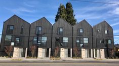 a row of black houses with white doors on the front and side of each building