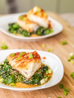 two white plates topped with food on top of a wooden table next to each other