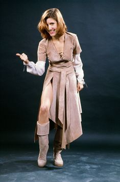 a woman in a trench coat and knee high boots is posing for a photo with her hands out