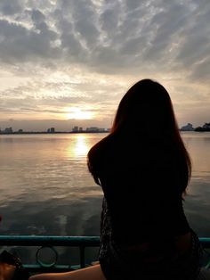 a woman sitting on a boat watching the sunset