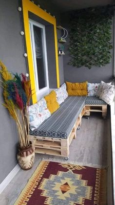 a couch sitting on top of a wooden pallet next to a rug and potted plants