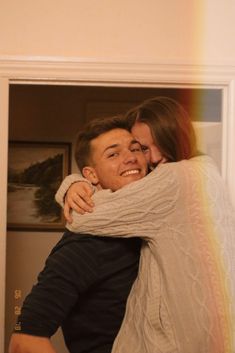 a man and woman hugging each other in front of a rainbow painted wall behind them