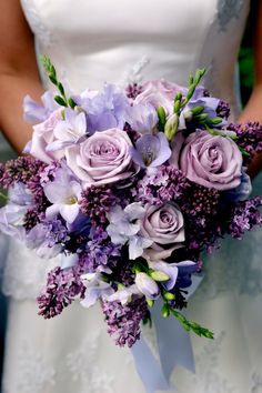 a bride holding a bouquet of purple flowers