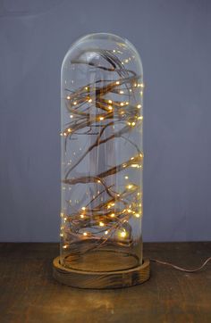 a glass jar filled with lights on top of a wooden table