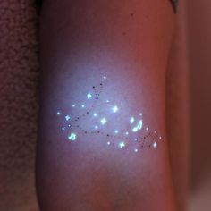 a woman's arm with white lights on it and stars in the middle of her arm