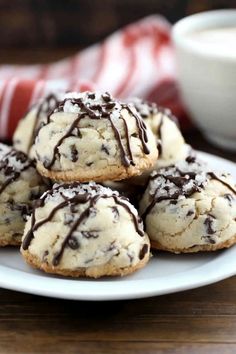 chocolate chip cookies on a white plate with a cup of coffee in the background