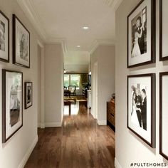 a hallway with pictures on the wall and wood flooring, along with framed photos