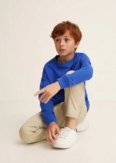 a young boy sitting on the ground wearing a blue shirt